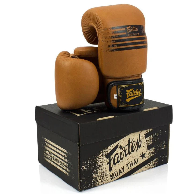 Pair of brown boxing gloves with black accents on a Fairtex branded box.