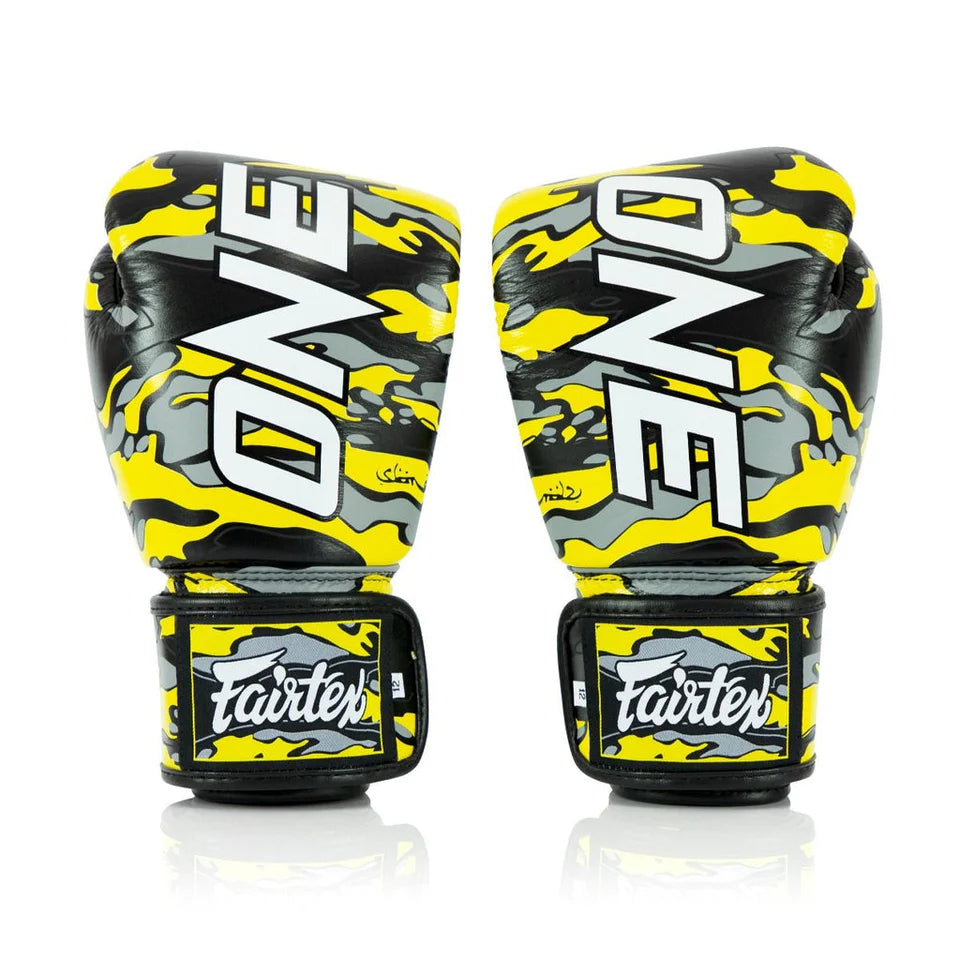 Pair of yellow and black boxing gloves with 'ONE' and 'Fairtex' branding on a white background.