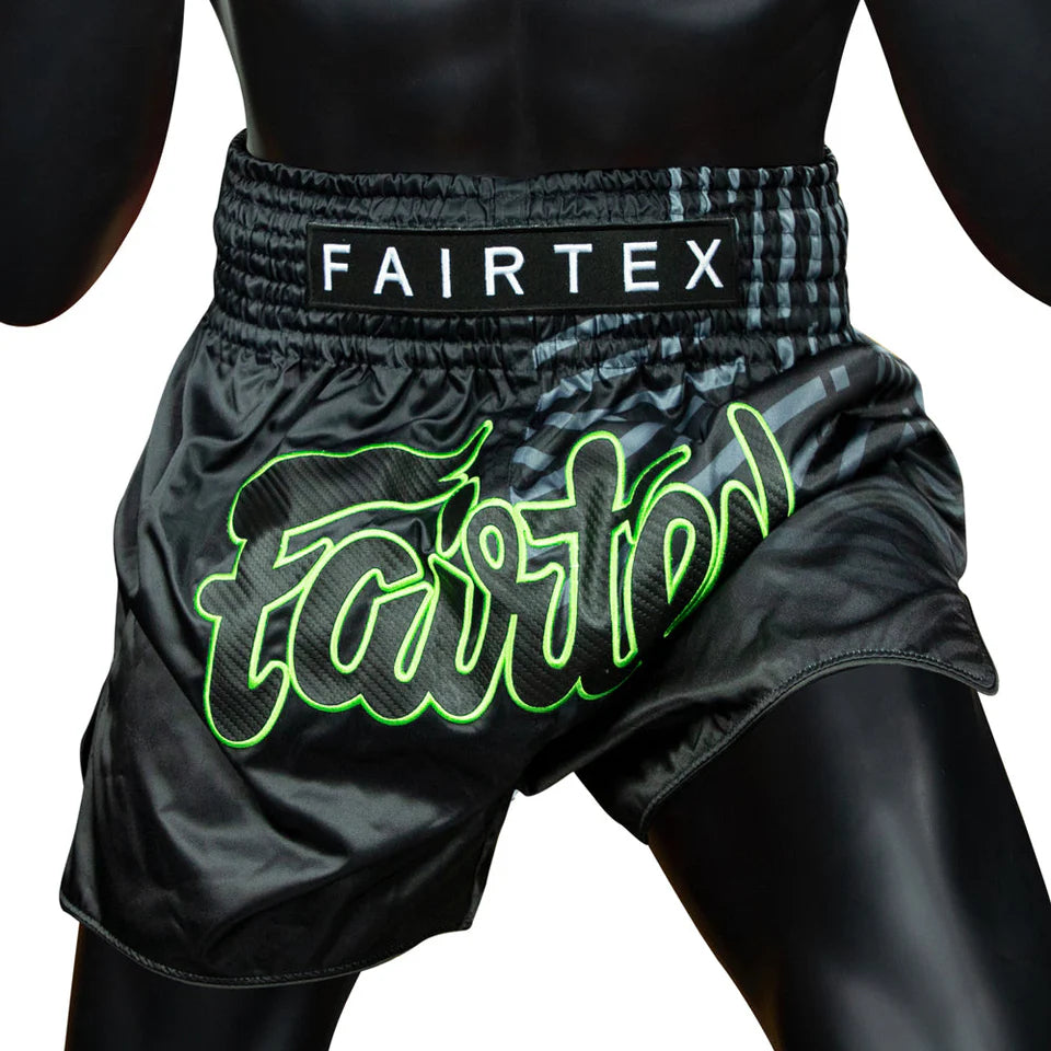 Black Fairtex Muay Thai shorts with green logo on a white background