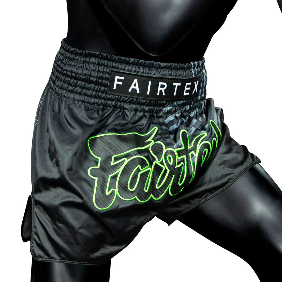 Black Fairtex Muay Thai shorts with green logo on a white background