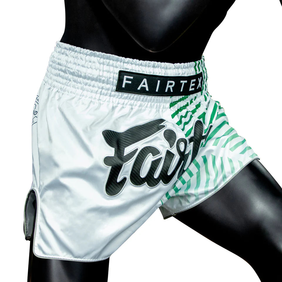 White Muay Thai shorts with green patterns and Fairtex branding on a white background