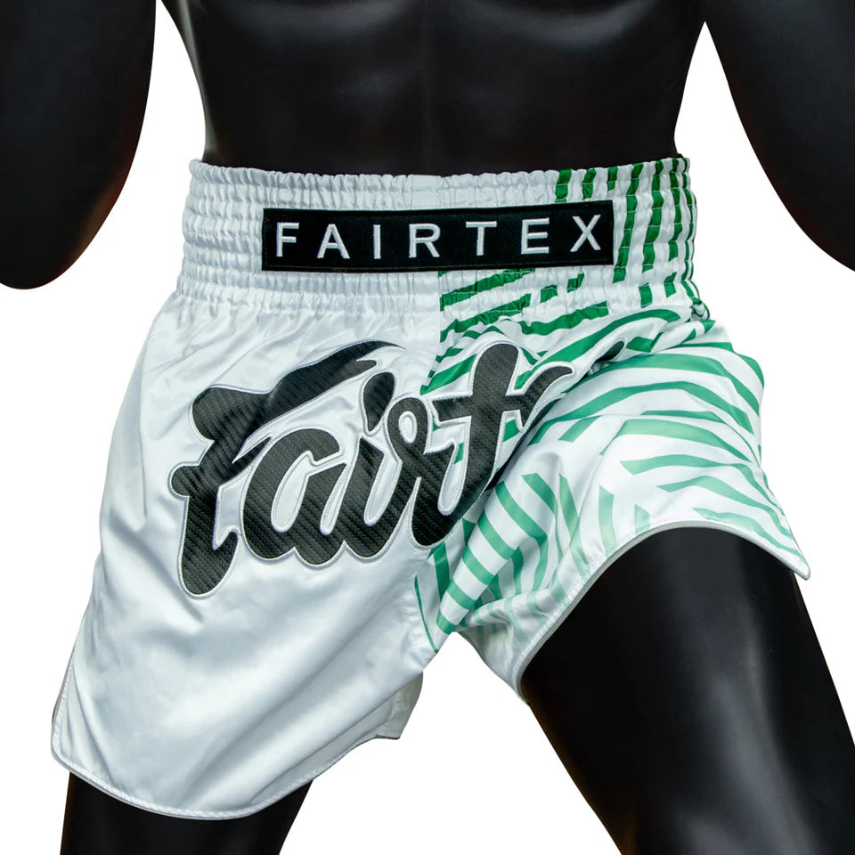 White and green Muay Thai shorts with 'Fairtex' branding on a black background