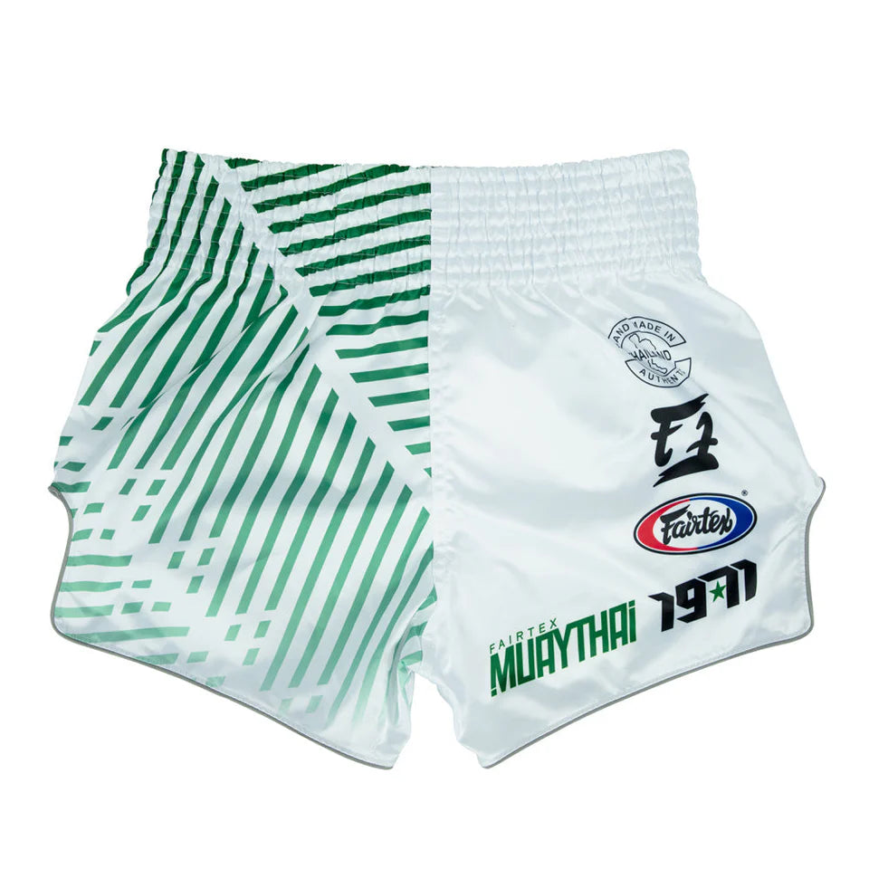 White Muay Thai shorts with green patterns and branding on a white background