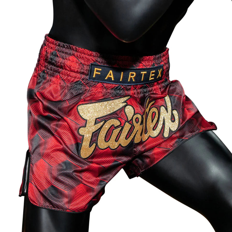 Red and black Muay Thai shorts with 'Fairtex' branding on a white background
