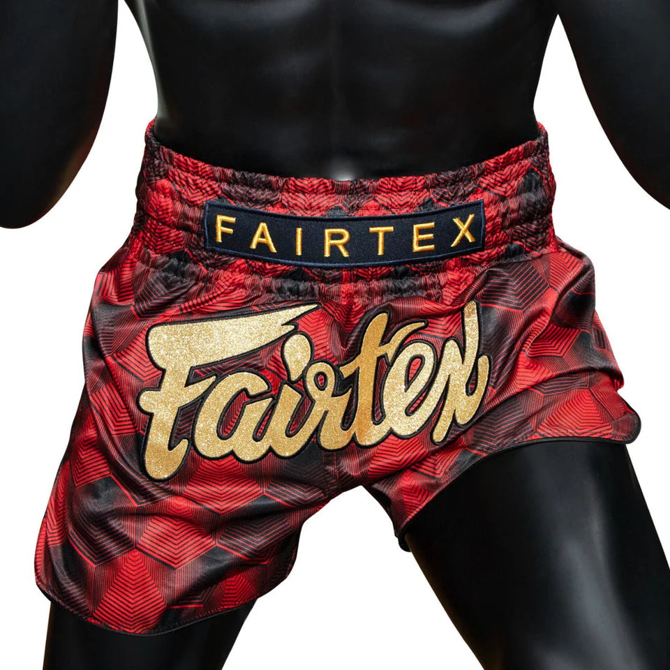 Red and black Fairtex Muay Thai shorts on a mannequin with a white background