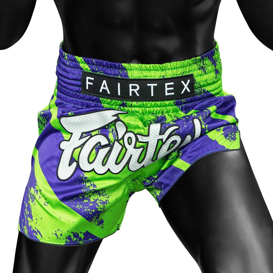 Green and purple Fairtex boxing shorts on a black mannequin.