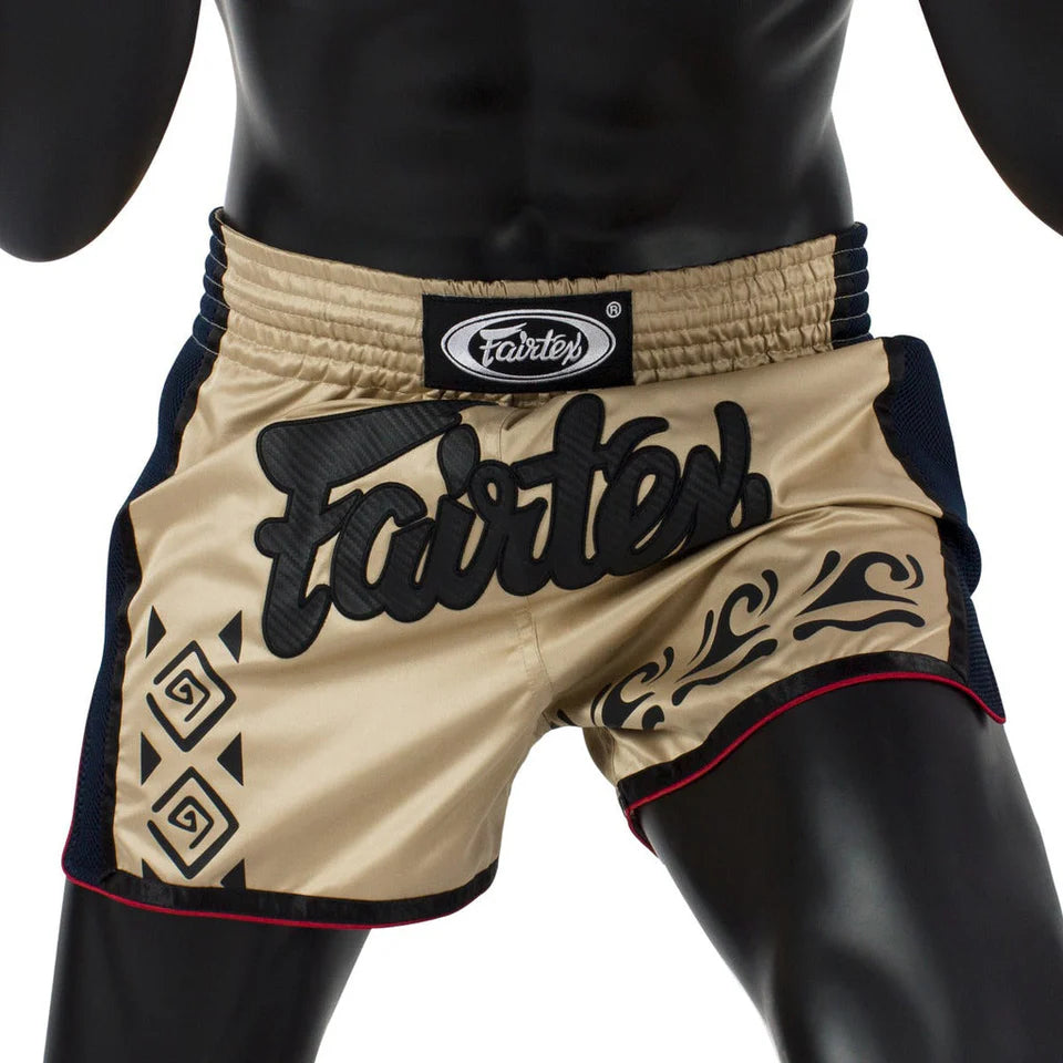 Beige and black Muay Thai shorts with 'Fairtex' branding on a mannequin.