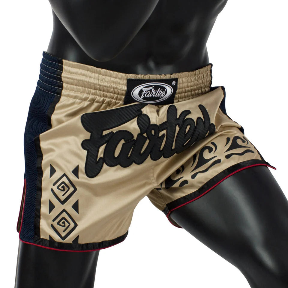 Beige Muay Thai shorts with black patterns and 'Fairtex' branding on a mannequin.