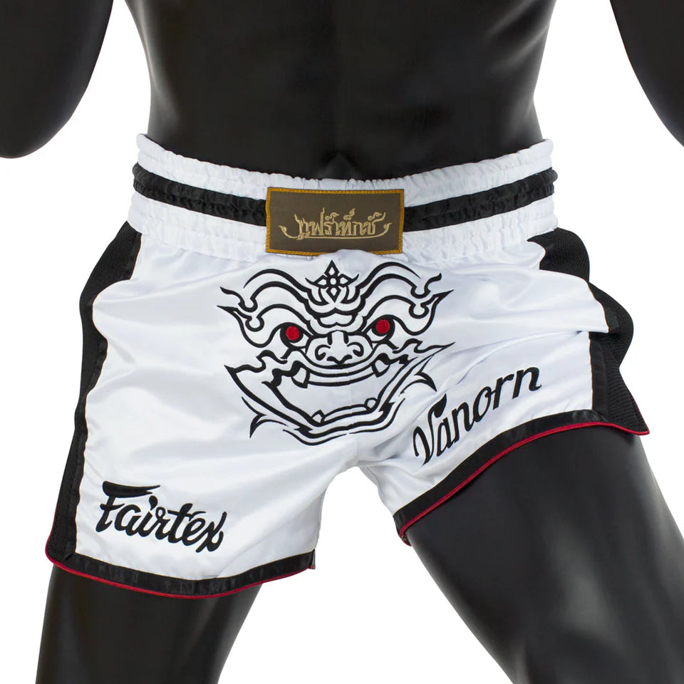 White Muay Thai shorts with black and red design on a mannequin, featuring 'Fairtex' branding.
