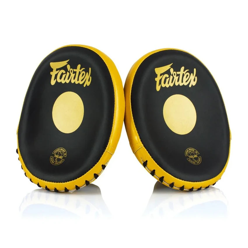 Pair of black and yellow Fairtex focus mitts on a white background