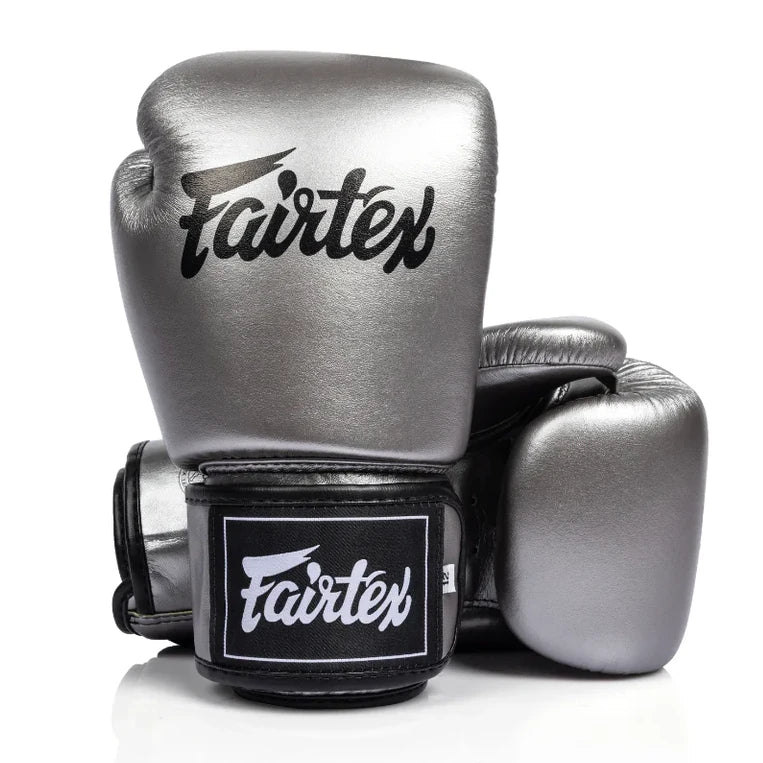 Pair of metallic boxing gloves with Fairtex logo on a white background