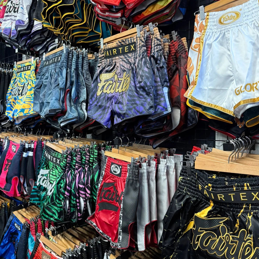 Display of various Thai boxing shorts on hangers with visible branding.