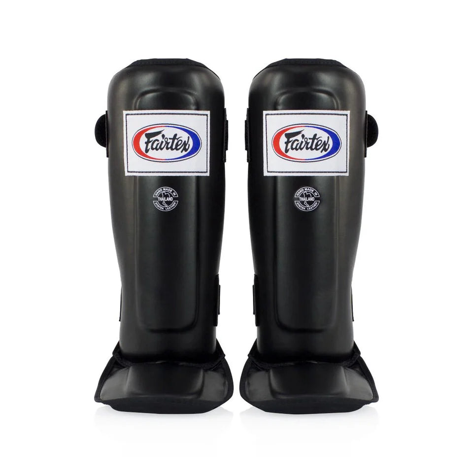 Pair of black Fairtex shin guards on a white background