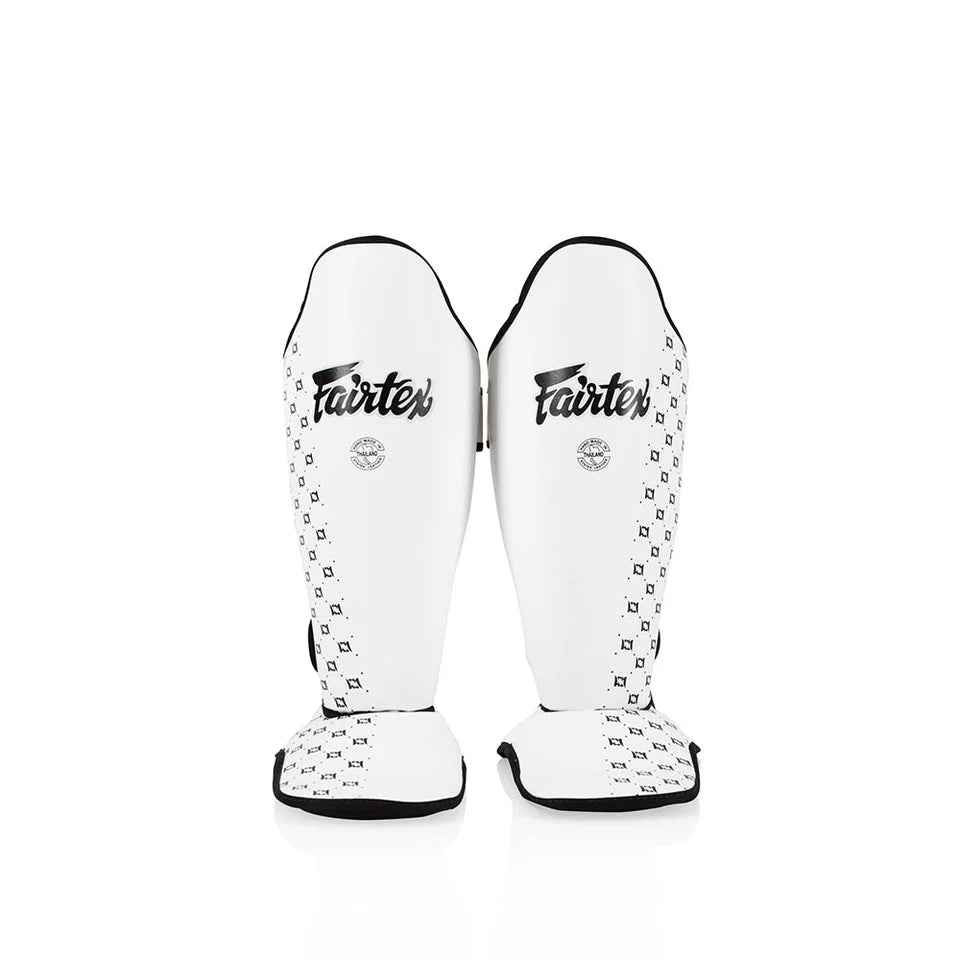Pair of white Fairtex shin guards on a white background