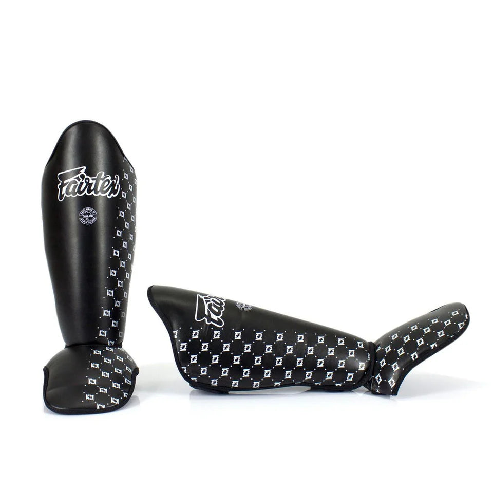 Black shin guards with white pattern and 'Fairtex' branding on a white background