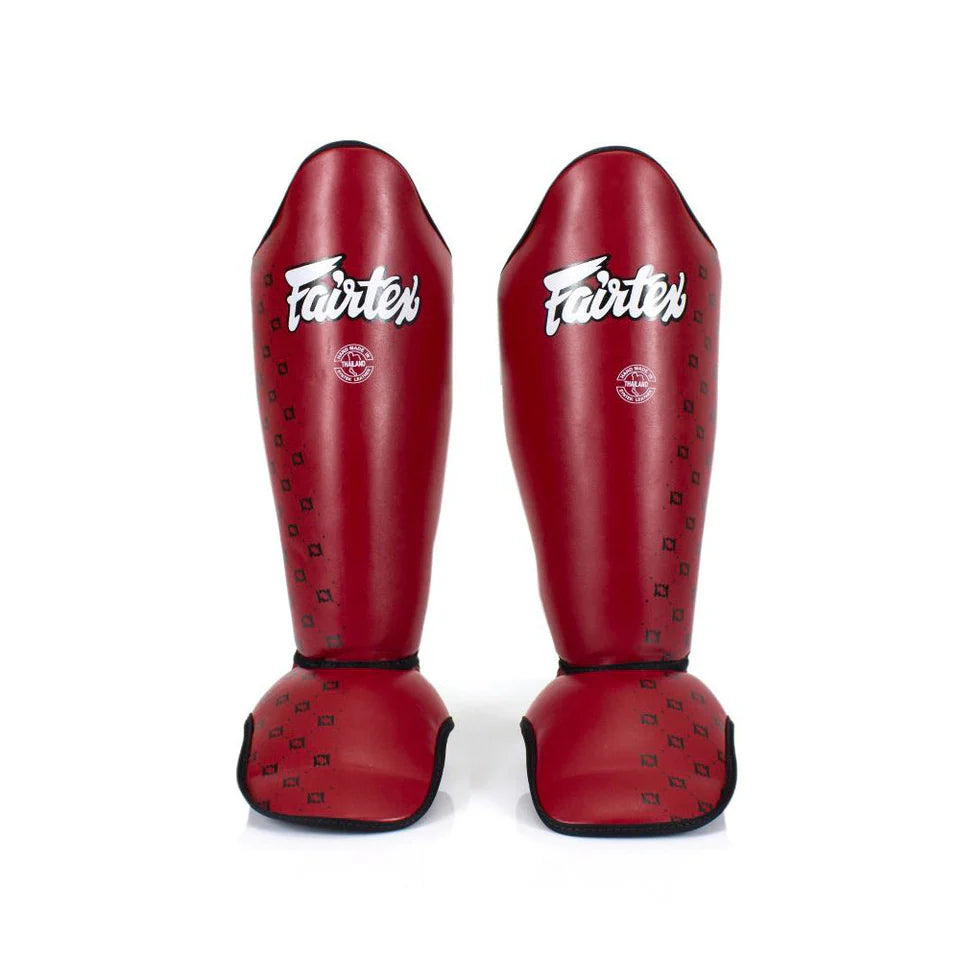 Pair of red Fairtex shin guards on a white background