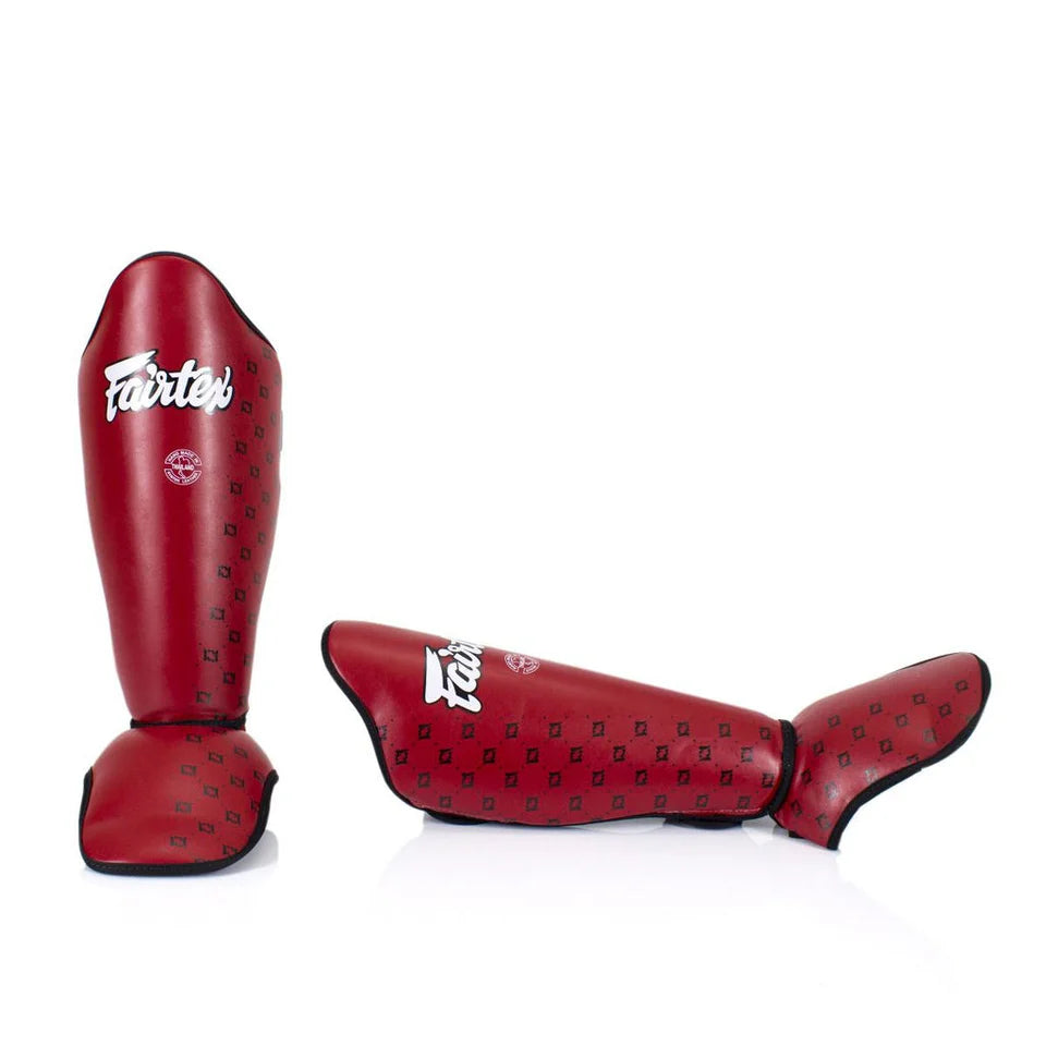 Red shin guards with black patterns and 'Fairtex' branding on a white background