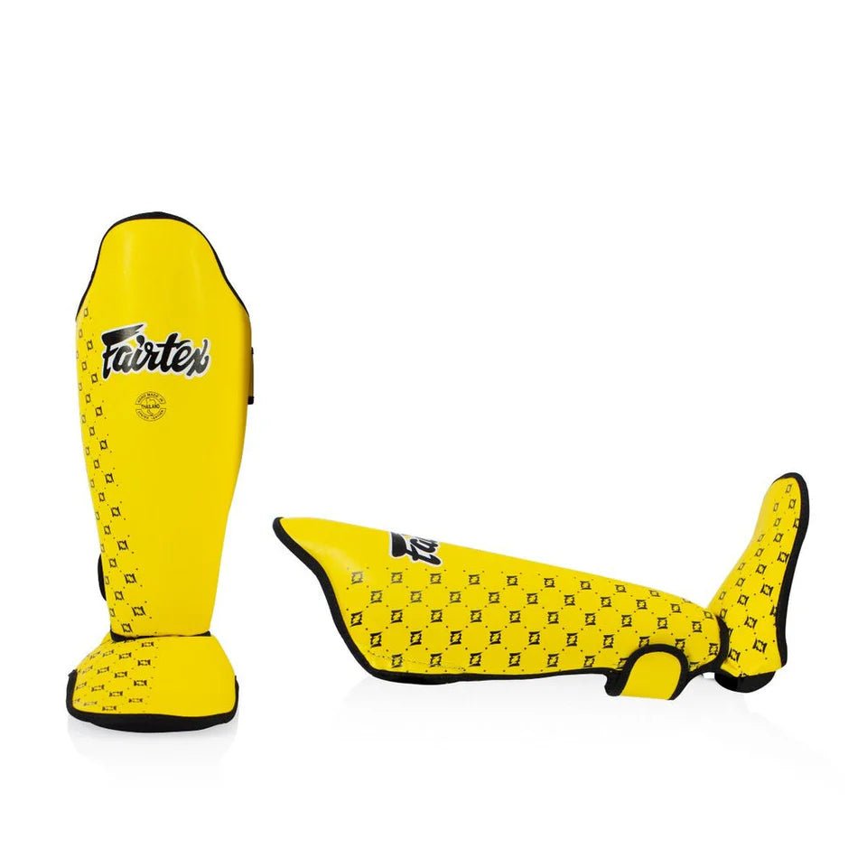 Yellow shin guards with black pattern on a white background, featuring the Fairtex brand.