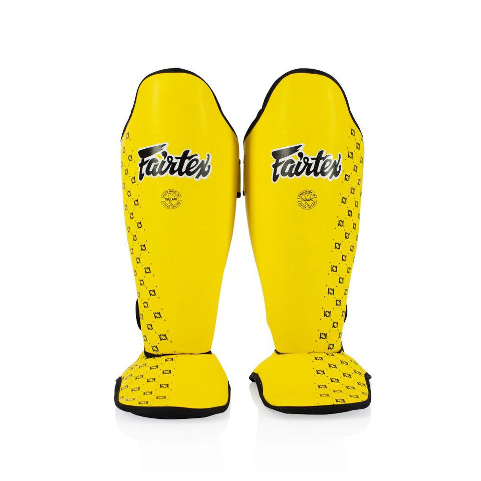 Pair of yellow Fairtex shin guards on a white background