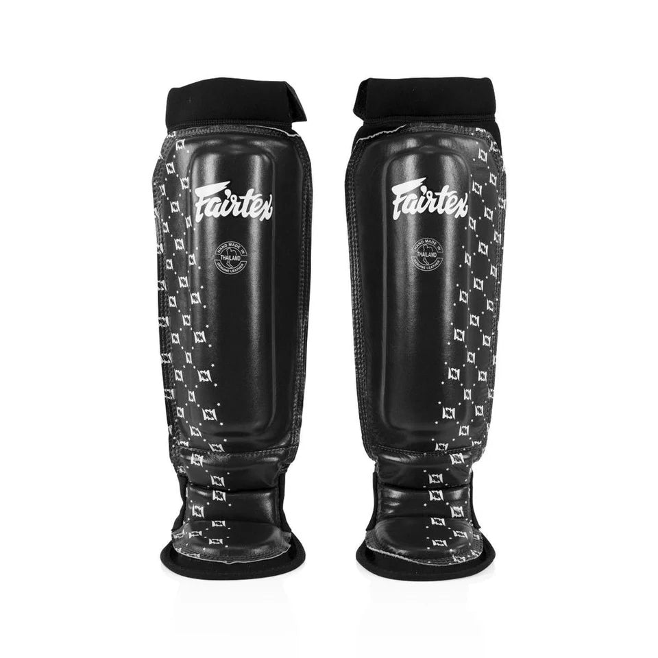 Pair of black Fairtex shin guards on a white background