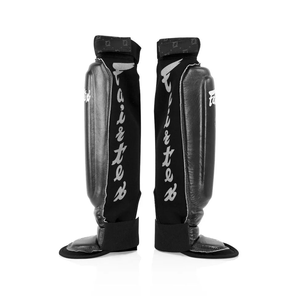Pair of black shin guards with 'Fairtex' branding on a white background