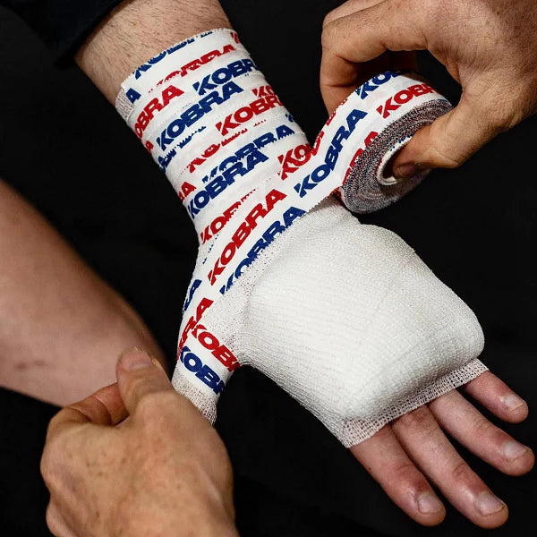 Person applying KOBRA brand tape on a dark background