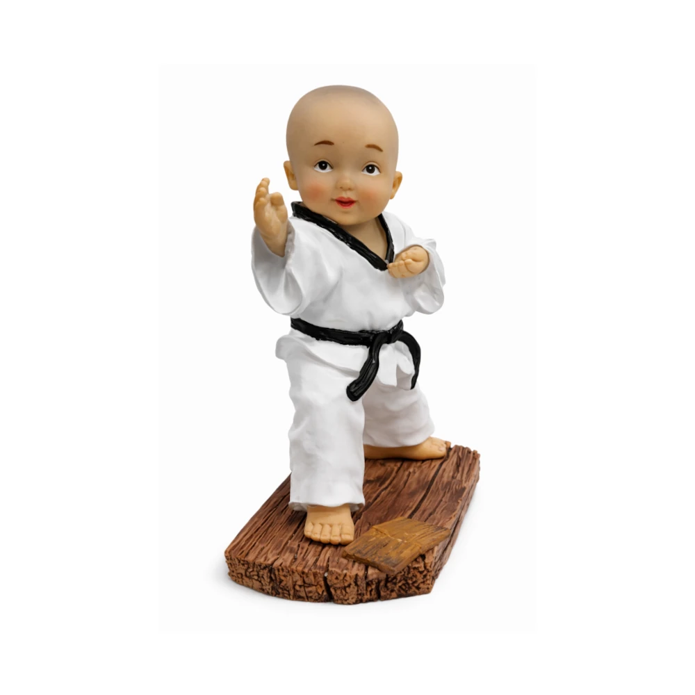 Figurine of a baby in a martial arts outfit with a black belt on a wooden platform.