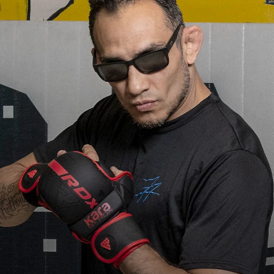 Man wearing black sunglasses and a black 'RDX Kara' glove against a gray background