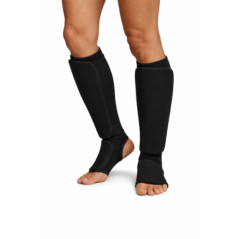 Black leg shin pad on a person's legs against a white background