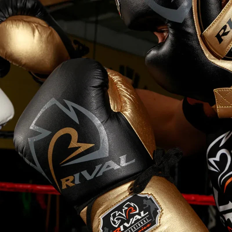 Close-up of black and gold RS100 boxing gloves with 'Rival' branding in a boxing ring.