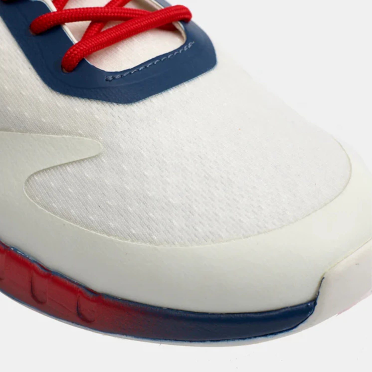 Close-up of a white sneaker with red and blue accents on a white background