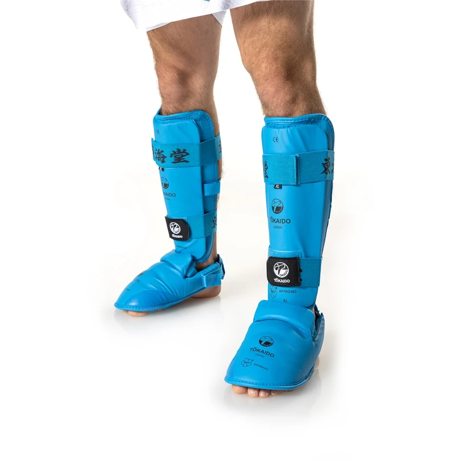 Blue Tokaido shin guards on a person's legs with a white background