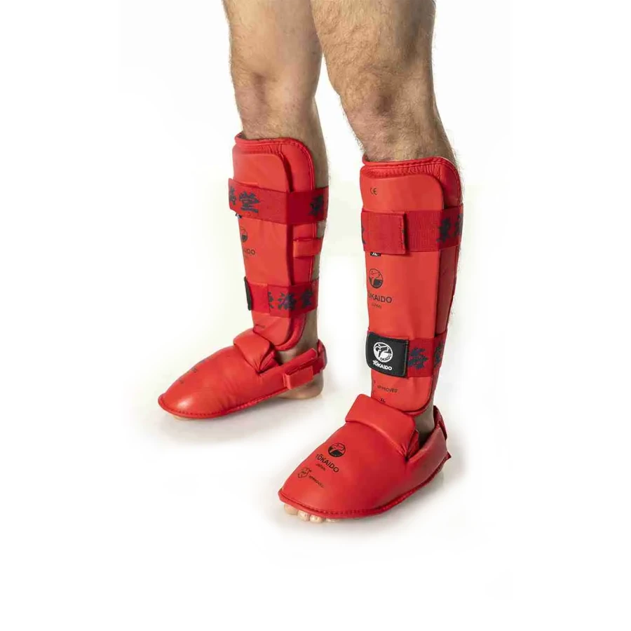 Red Tokaido shin guards on a person's legs with a white background