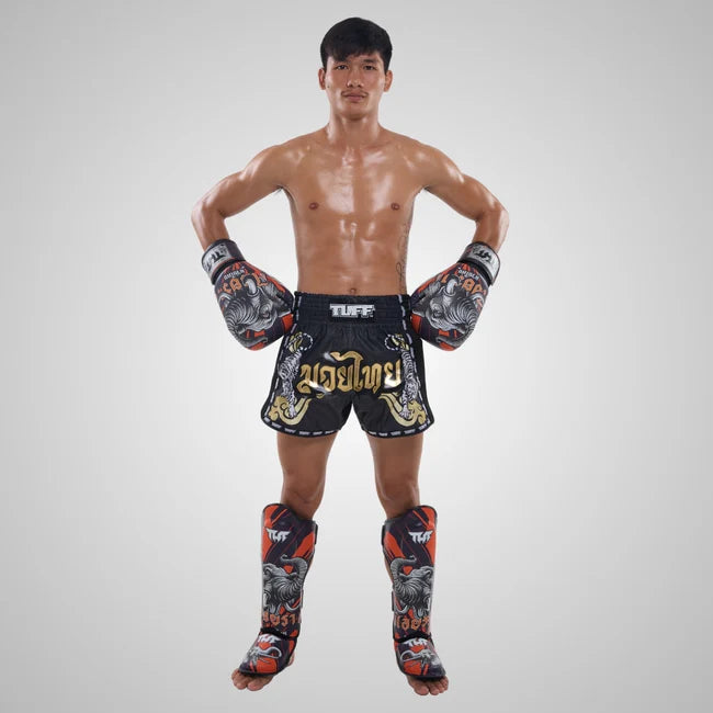 Man wearing TUFF Muay Thai shorts and gloves on a gray background