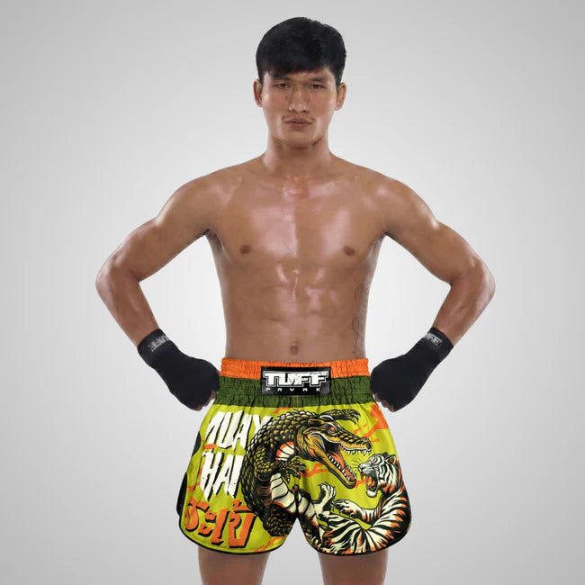 Man wearing colorful Thai boxing shorts with a crocodile and tiger design on a gray background