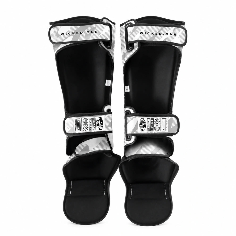 A pair of black and white patterned shin guards with adjustable straps, displayed against a solid white background.