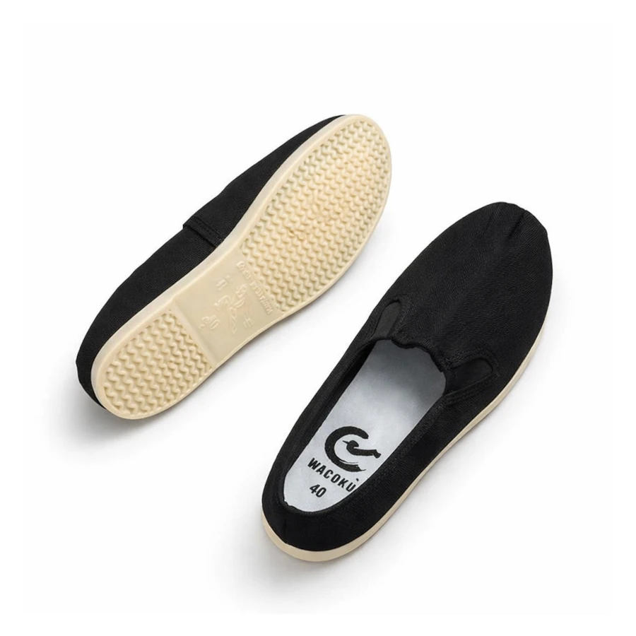 Black slip-on martial arts shoes with beige soles on a white background