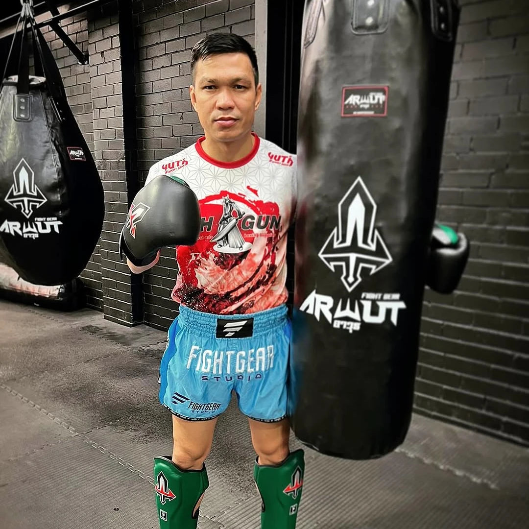 Person in boxing gear standing next to a punching bag with 'Arwut' branding.